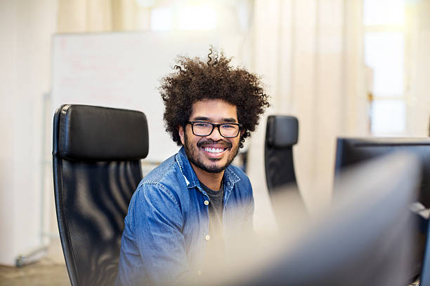 istock Happy african man sitting at his desk and smiling 613115400