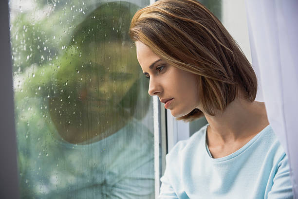 istock sad woman sitting indoors while raining 613118022