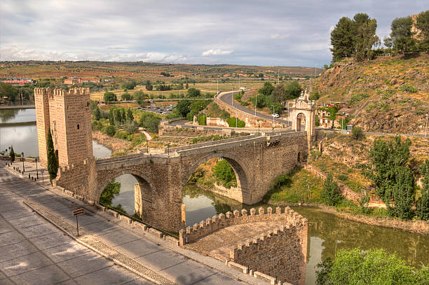 Historical stone Alcantara Bridge across the river Tagus, leading into the historical city of Toledo, Spain