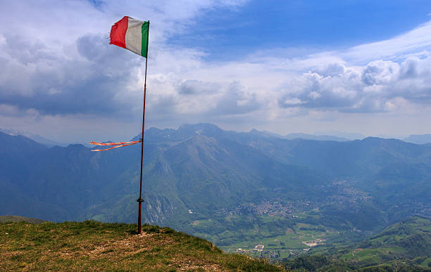 istock Alps italian flag in a cloudly sky 613118744