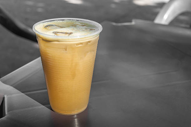 Sugarcane juice, a yellow drink that should be drunk cold. Very sweet, it contains much sugar and is natural. Glass of sugarcane juice on the bar table in a plastic cup.