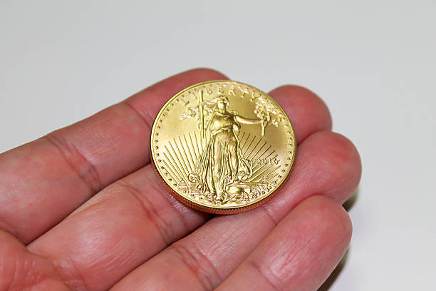 istock Gold Coin Held by Human Fingers 613128526
