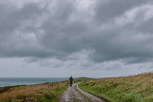 istock man on Coast footpath, Newquay, Cornwall in overcast gloomy weather. 613130450