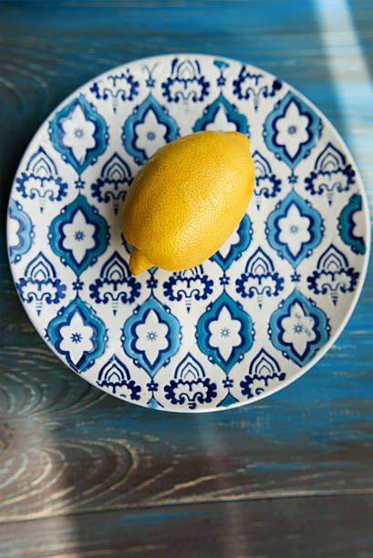 istock Yellow fresh lemon on the plate with blue pattern 613131338