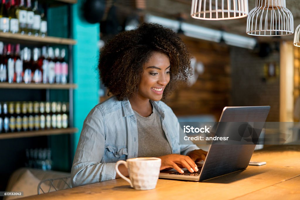 Casual woman working at a cafe Casual woman working at a cafe using a laptop computer and looking happy Owner Stock Photo