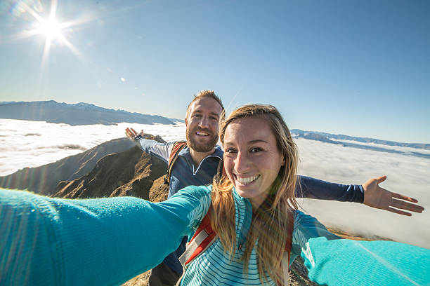 istock Young couple on mountain peak take selfie portrait, above clouds 613132720