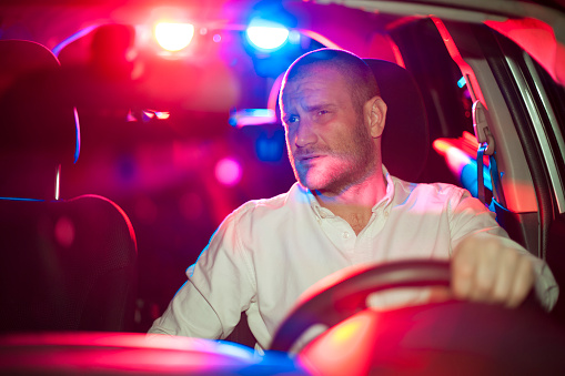 Guy in a car, trying to escape police. He's been involved in a police pursuit for a while now which made him quite nervous about getting caught.