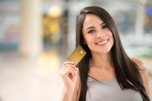 Beautiful shopping woman holding a credit card and looking very happy. Design on credit card is own design