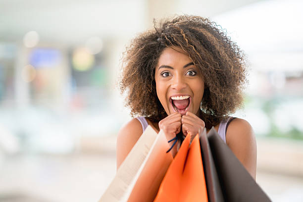 Excited woman having fun shopping Excited woman having fun shopping and holding bags while looking at the camera smiling spree river stock pictures, royalty-free photos & images