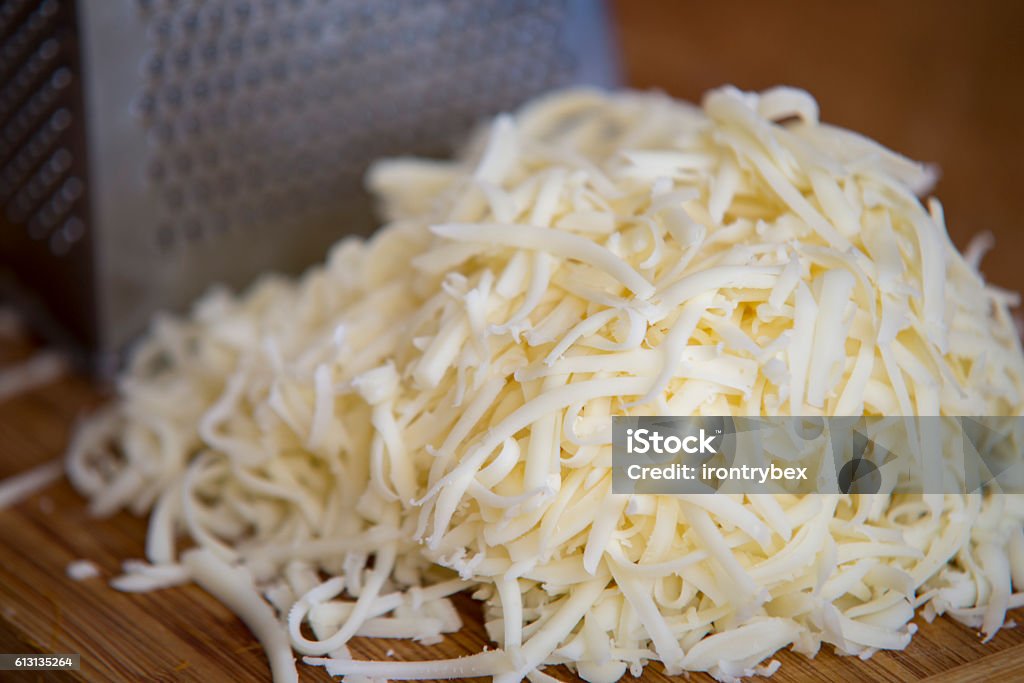 Mozzarella triturata su tagliere con grattugia - Foto stock royalty-free di Mozzarella