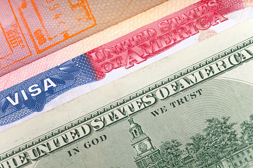 The American visa on page of the international passport and US dollars, closeup
