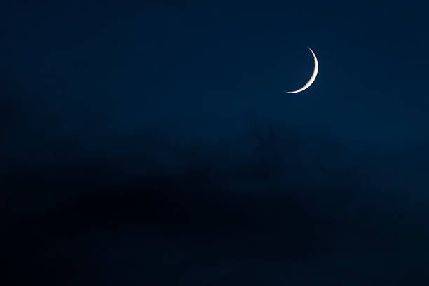 Crescent Moon in Cloudy Sky at Night stock photo