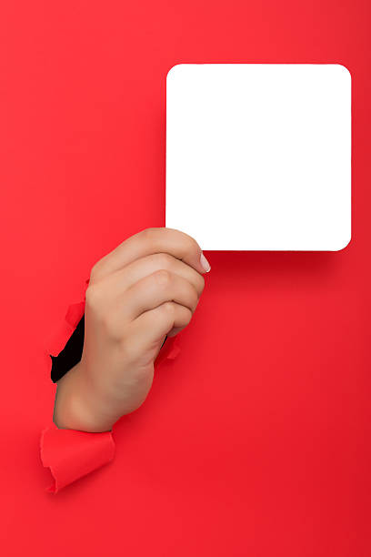 istock Female hand reaching through torn red paper sheet 613143648