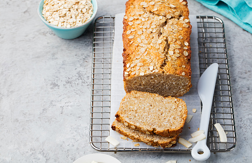 Healthy vegan oat and coconut loaf bread, cake on a cooling rack Grey stone background Copy space