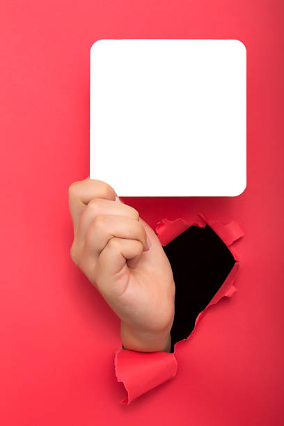 istock Female hand reaching through torn red paper sheet 613143782