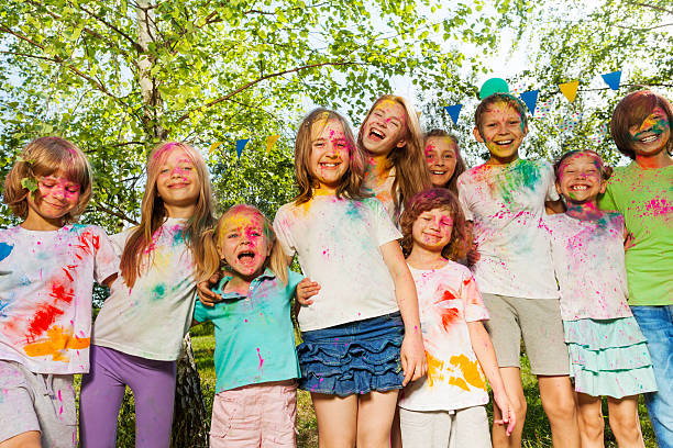 istock Kids smeared with colored powder standing in a row 613143856