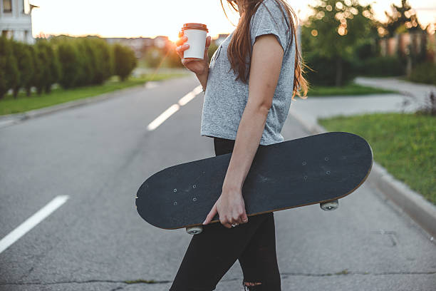 istock beautiful girl with skateboard drinks coffee from white to-go cup 613145172