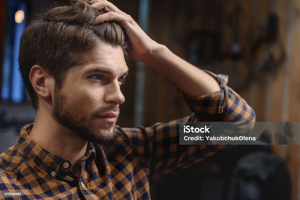 face of male client visiting hairstylist selective focus on bearded guy touching his hair, beauty concept Adult Stock Photo