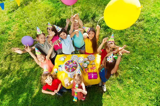 Photo of Group of laughing kids standing around B-day cake