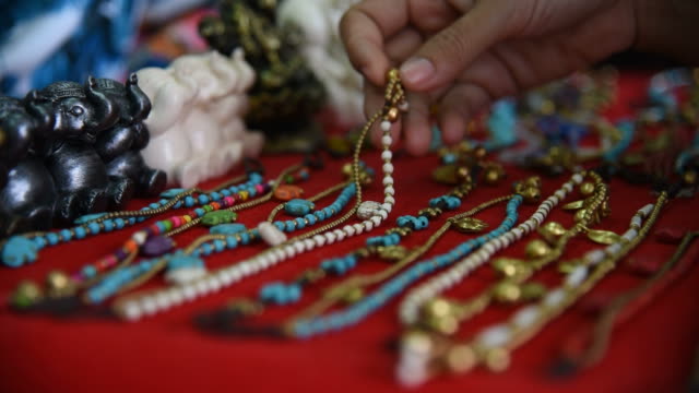 Woman tourist choosing a bracelet at souvenir shop in Thailand.