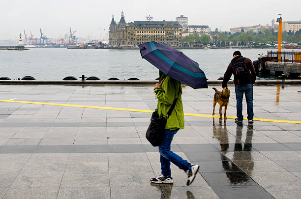 Istanbul steamboat pier people walking in the rain. Istanbul, Turkey - April 18, 2014: Istanbul Kadikoy Steamboat pier and Haydarpasa train station building.  People walking in the rain pier. Strait of Istanbul, Kadikoy Pier, ferries are the most popular form of public transport in Istanbul for. haydarpaşa stock pictures, royalty-free photos & images