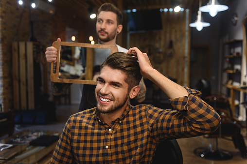 looking perfect, satisfied young handsome man smiling in hair salon