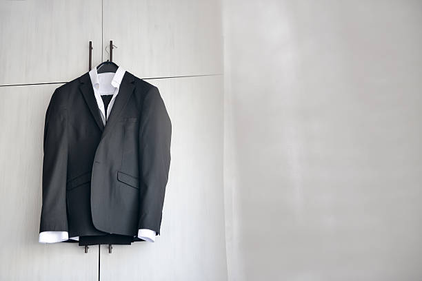 istock Black suit hanged to a wood closet in natural light 613211264