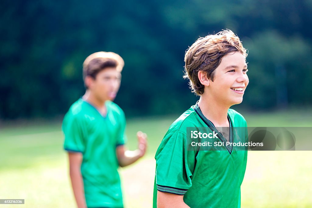 Happy athlete during soccer game Handsome teenage soccer athlete smile confidently during soccer game. They are wearing green uniforms. Kids' Soccer Stock Photo