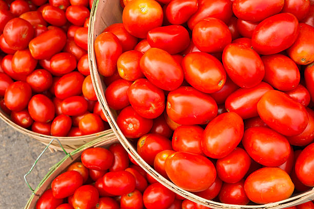 многие цыганские помидоры в корзинах на рынке - plum tomato фотографии стоковые фото и изображения