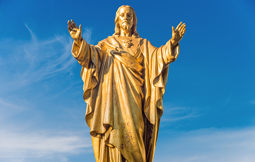 Old Jesus Christ golden statue isolated over blue sky