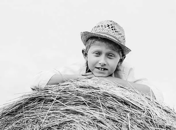 Boy in straw hat lying on the haystack BW