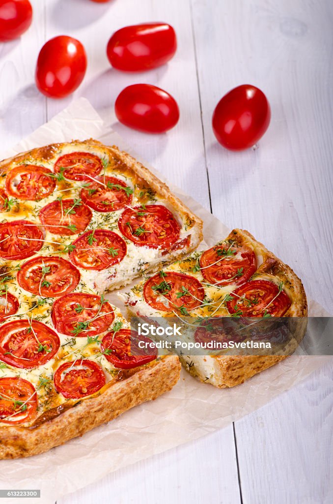 Tart with tomato and fresh herbs Tart with tomato and fresh herbs on a white wooden table. Healthy eating, Vegetable Pie. Appetizer Stock Photo