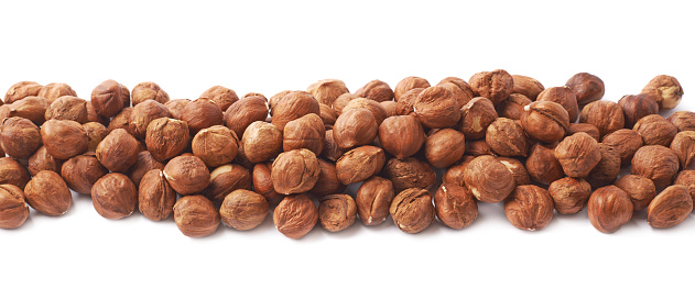 Multiple hazelnuts aligned in a line as copyspace background composition isolated over the white background
