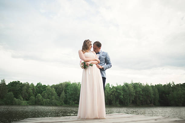 istock Bride and groom walking on the river, smiling, kissing 613226428