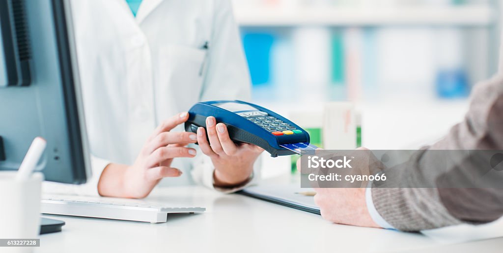 Man purchasing products in the pharmacy Man purchasing products in the pharmacy, he is paying with a credit card using a terminal Paying Stock Photo
