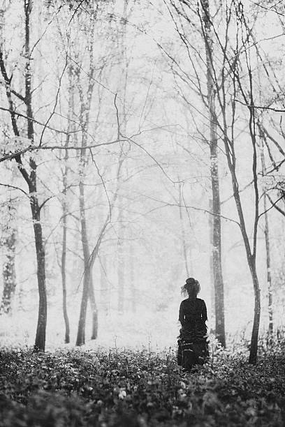 Woman in black Black and white image of woman in a black victorian dress in a misty late autumn forest. mourner photos stock pictures, royalty-free photos & images