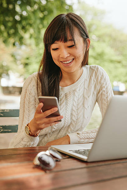 istock Smiling woman using cellphone at coffee shop 613229620