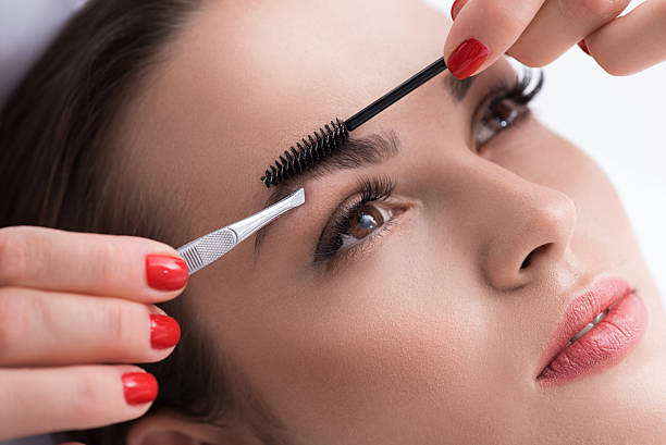 istock Skillful beautician tweezing human brows 613231752