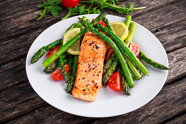 istock Fried salmon with asparagus, tomatoes, lemon, yellow lime on white 613232234