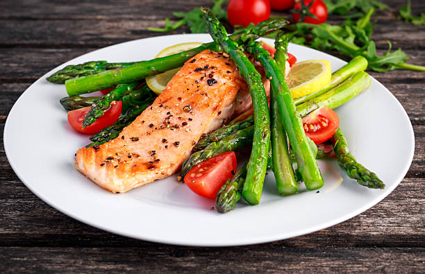 istock Fried salmon with asparagus, tomatoes, lemon, yellow lime on white 613232340