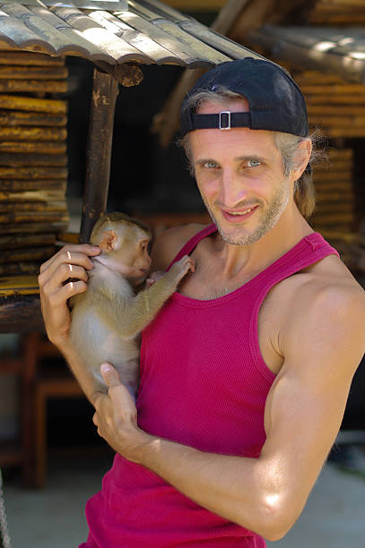 istock man holds a young Rhesus Macaque Macaca mulatta on arms 613232918