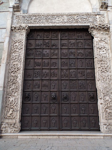 Benevento, Campania, Italy - July 3, 2016: the massive bronze doors on the facade of Benevento cathedral dedicated to Santa Maria Assunta. It was built in 2012 as a complete copy of the original, restored in the nineties as a result of the bombing in 1943 that reduced to fragments, placed inside as a gateway to the nave.