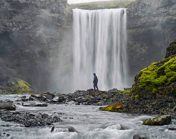 istock Man dressed  standing at the base of a waterfall 613238936