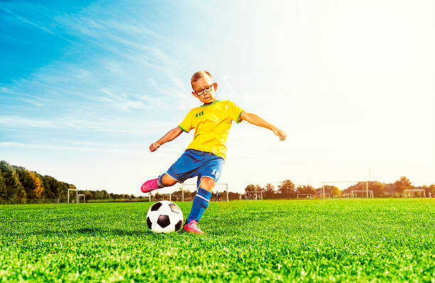 ragazzo gioca a calcio in campo e calcia a calcio - kick off soccer player soccer kicking foto e immagini stock