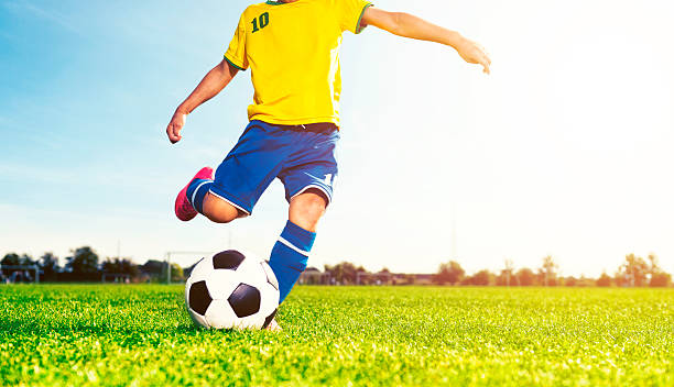 istock Boy kicks soccer ball while playing a football match 613240116