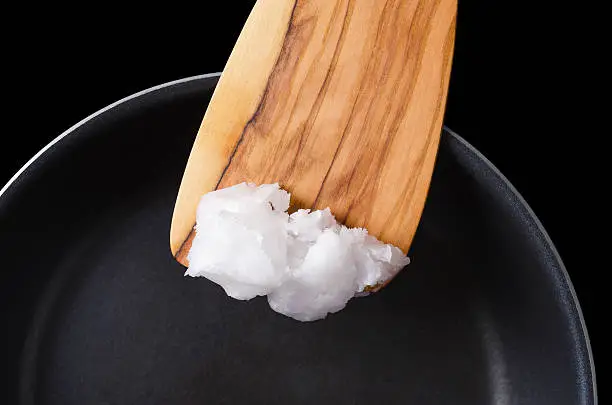 Photo of Coconut oil on wooden spatula over coated pan