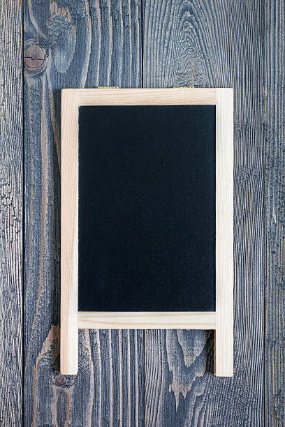 istock Black empty chalkboard on wooden table for copy space, vertical 613241786