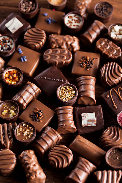 istock Chocolate bars and pralines on wooden background 613242594