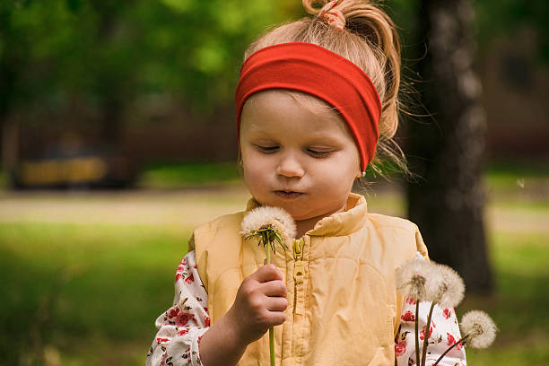 Beautiful child with dandelion flower in spring park.