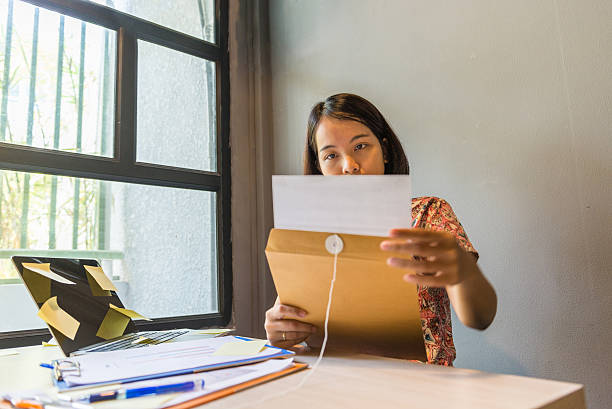 istock Female holding file and working with laptop beside window 613244652